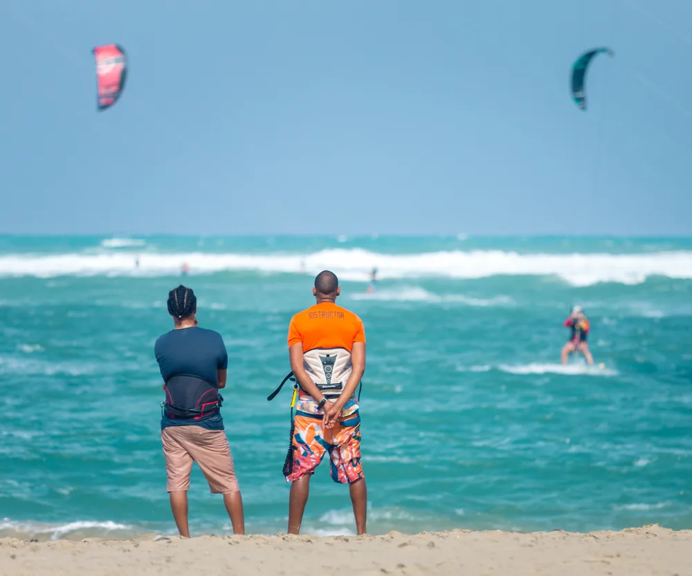 Two riders watching kitesurfers from the beach in Cabarete