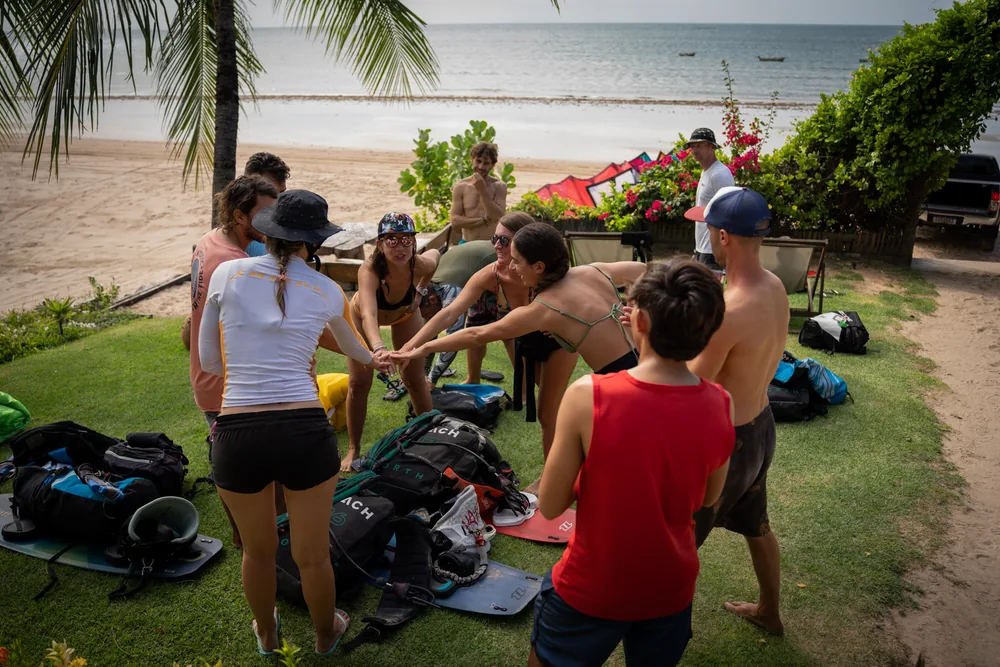 A group of riders joins hands beside their equipment overlooking the sea